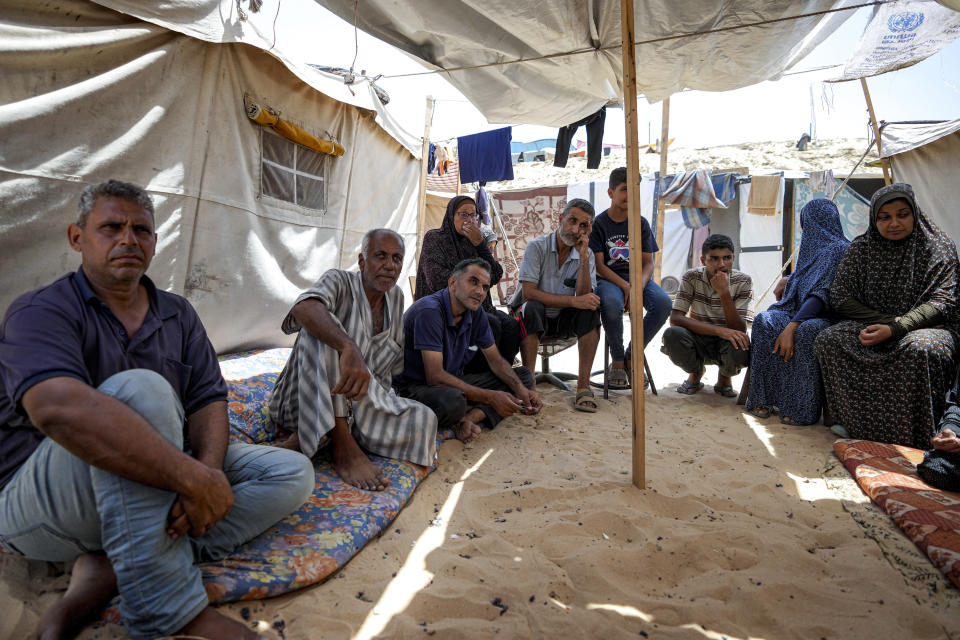 Members of the Al-Ashqar family, who were displaced by the Israeli bombardment of the Gaza Strip, sit at a makeshift tent camp in Khan Younis, southern Gaza Strip, Thursday, July 4, 2024. Over nine months of war between Israel and Hamas, Palestinian families in Gaza have been uprooted repeatedly, driven back and forth across the territory to escape the fighting. Each time has meant a wrenching move to a new location and a series of crowded, temporary shelters. (AP Photo/Abdel Kareem Hana)