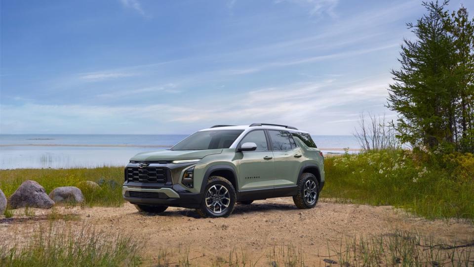 front 34 view of a 2025 chevrolet equinox activ in cacti green parked in front of a lake preproduction model shown actual production model may vary model year 2025 chevrolet equinox available 2024