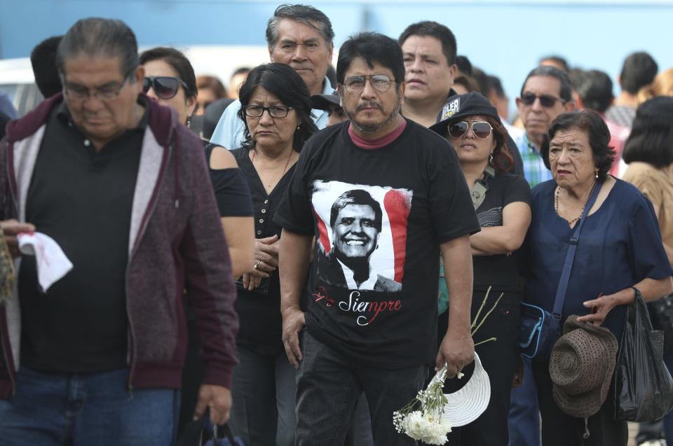 A man wearing a T-shirt featuring Peru's late President Alan Garcia arrives with others to Garcia's political party headquarters where his wake is taking place in Lima, Peru, Friday, April 19, 2019. Garcia shot himself in the head and died Wednesday as officers waited to arrest him in a massive graft probe that has put the country's most prominent politicians behind bars and provoked a reckoning over corruption. (AP Photo/Martin Mejia)