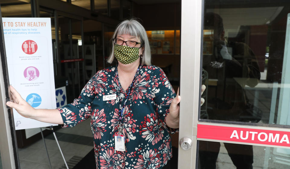 Librarian Holly Ryckman opens the front door of the Davis Library in Plano, Texas Friday, May 15, 2020. Ryckman is participating in a program that have popped up across the U.S. during the pandemic to help older adults with a simple offer to engage in small talk. Ryckman regularly chats with 81-year-old Dell Kaplan via phone. Kaplan, who retired 11 years ago after more than two decades managing Plano's senior center, said she and Ryckman didn't know each other, but found common ground in talking about the city and dealing with isolating at home. Ryckman said the calls have been "a gift" for her. (AP Photo/LM Otero)