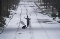 Children play with a sled as snow begins to accumulate, Thursday, Feb. 18, 2021, in San Antonio. Snow, ice and sub-freezing weather continue to wreak havoc on the state's power grid and utilities. (AP Photo/Eric Gay)