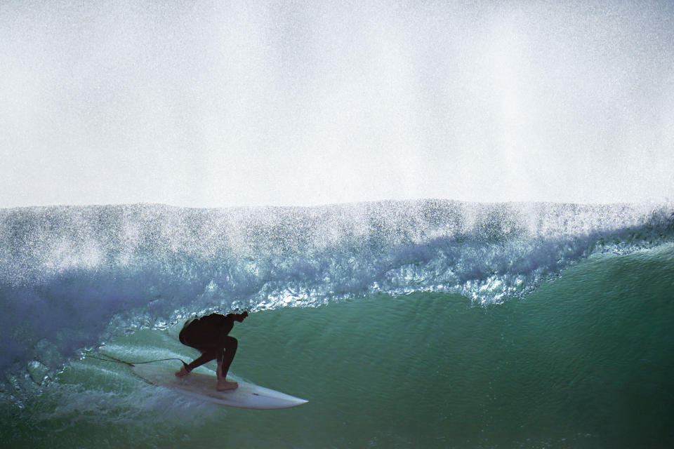 Un surfista monta una ola en la playa Blacks en San Diego el 12 de enero de 2022, mientras una ronda de grandes olas surca la zona. (AP Foto/Gregory Bull)