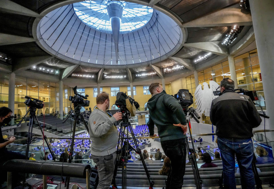 Media people watch a debate about a vaccination mandate at the parliament Bundestag in Berlin, Germany, Wednesday, Jan. 26, 2022. (AP Photo/Markus Schreiber)