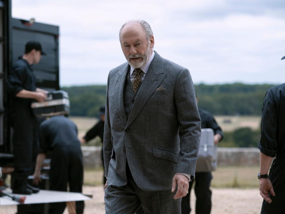 liam cunningham as wade in 3 body problem, wearing a thre epiece grey suit and moving around outside