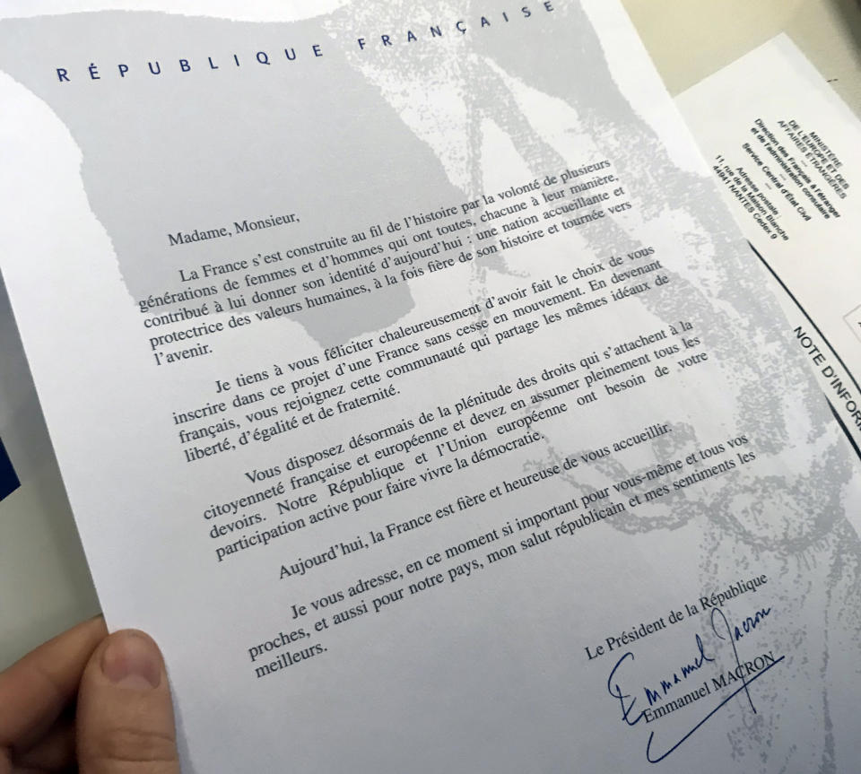 A document signed by French President Emmanuel Macron and given to Britain's Catherine Norris Trent holds is pictured during a naturalization ceremony in Paris' Pantheon monument, Thursday, March 21, 2019. With the looming Brexit deadline, the 38-year-old mother of two who's lived in the French capital for over a decade was one of dozens of newly-minted French nationals attending the ceremony. (AP Photo/Thomas Admason)