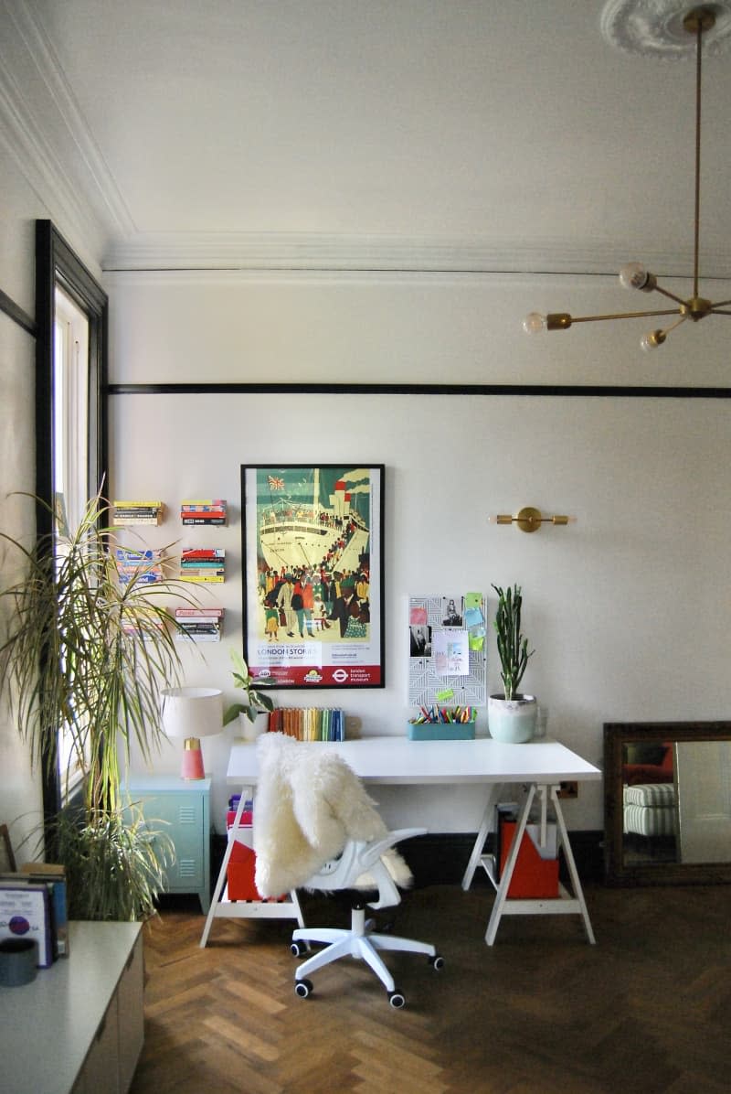 White desk space with a white desk below a framed piece of art.