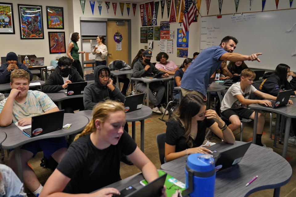 Westwood High School teacher Shaun Reedy instructs students, Tuesday, Oct. 18, 2022 in Mesa, Ariz. Like many school districts across the country, Mesa has a teacher shortage due in part due to low morale and declining interest in the profession. Five years ago, Mesa allowed Westwood to pilot a program to make it easier for the district to fill staffing gaps, grant educators greater agency over their work and make teaching a more attractive career. The model, known as team teaching, allows teachers to combine classes and grades rotating between big group instruction, one-on-one interventions, small study groups or whatever the team agrees is a priority each day. (AP Photo/Matt York)