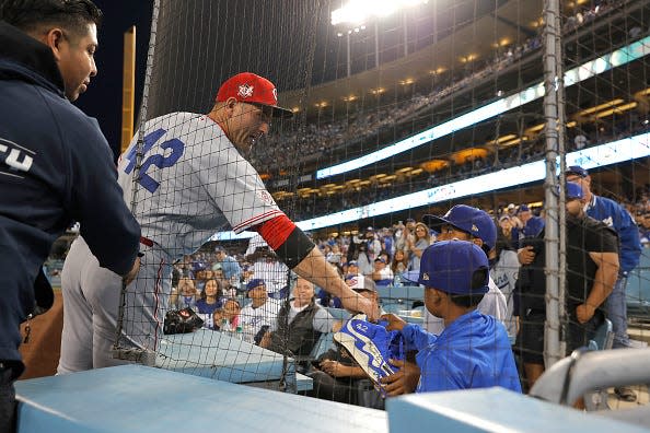 Joey Votto #19 of the Cincinnati Reds gives away his game worn signed cleats to a fan during the second inning of a game against the Los Angeles Dodgers at Dodger Stadium on April 15, 2022 in Los Angeles, California. All players are wearing the number 42 in honor of Jackie Robinson Day.