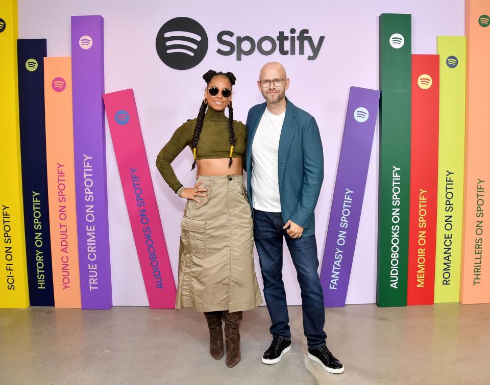 Alicia Keys and Daniel Ek stand in front of a wall made to look like a giant bookshelf.