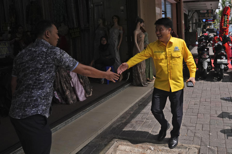 Chong Sung Kim, a Golongan Karya party legislative candidate, right, shakes hands with a shop attendant during his campaign at a shopping center in Jakarta, Indonesia, Tuesday, Jan. 30, 2024. As Indonesia votes this month to replace popular President Joko Widodo, all three candidates have all been aggressively seeking to win the votes of younger people, reaching out to them on the apps they use, through the K-pop music many love, and even video gaming events. (AP Photo/Dita Alangkara)