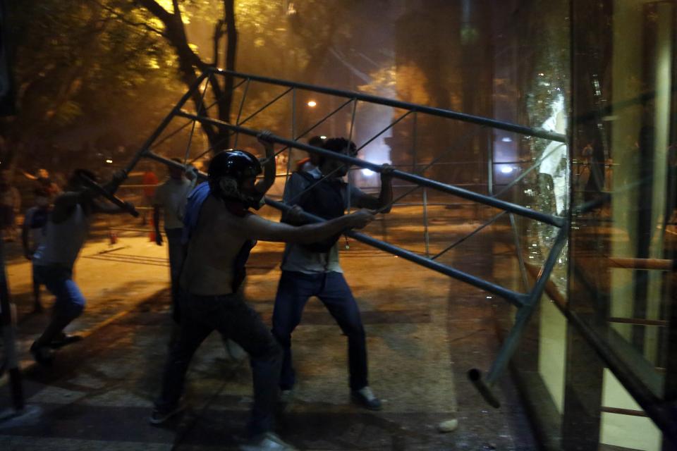 Manifestantes chocan contra una barrera en el edificio del Congreso durante enfrentamientos con la policía. Quienes protestaban se oponen a un proyecto de enmienda constitucional que permitiría la reelección presidencial en Asunción, Paraguay, el viernes 31 de marzo de 2017. Algunos manifestantes lograron sobrepasar a la policía y llegar hasta el primer piso, donde prendieron fuego a muebles y papeles. La policía usó carros hidrantes y balas de goma para dispersar a quienes protestaban afuera del edificio, mientras los bomberos enfrentaban el fuego en el interior. (AP Foto/Jorge Saenz)