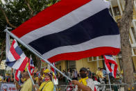 Supporters of the monarchy wave Thai national flags and display images of King Maha Vajiralongkorn, Queen Suthida and late King Bhumibol Adulyadej as they gather at Democracy Monument ahead of a pro-democracy demonstration in Bangkok, Thailand Sunday, Nov. 8, 2020. Thai royalists have recently been holding counter-demonstrations, but so far, they have lacked the numbers and enthusiasm of the pro-democracy activists. (AP Photo/Sakchai Lalit)