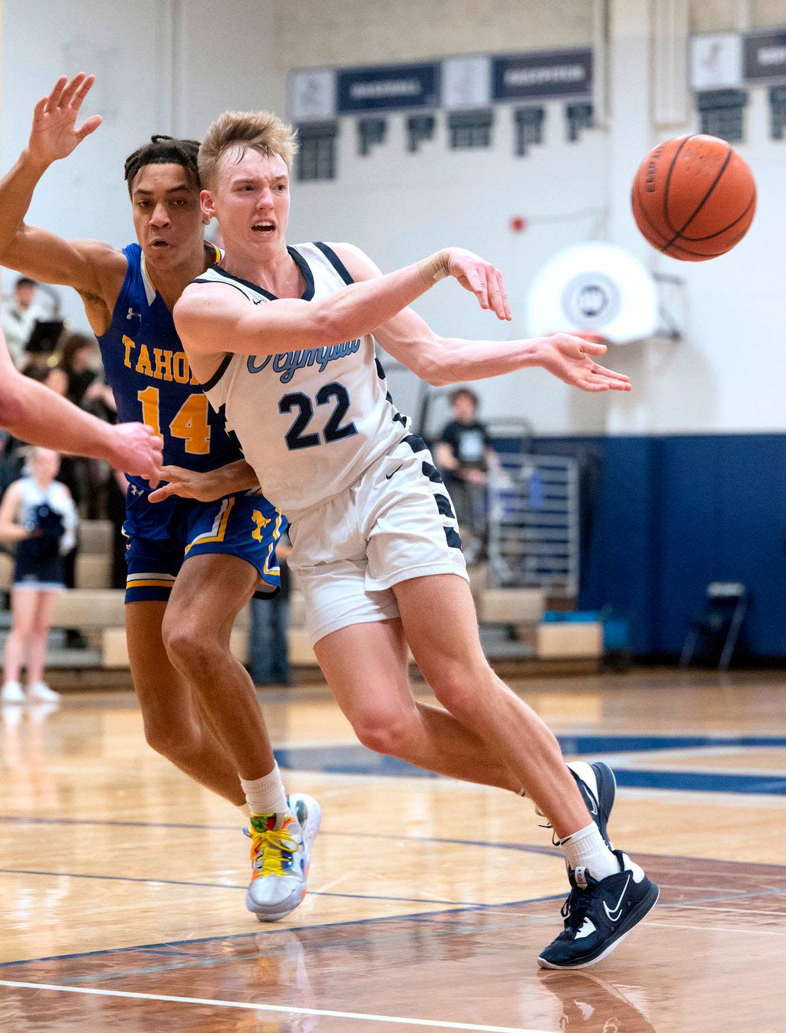 Olympia’s Parker Gerrits dishes off a pass in front of Tahoma defender Treyson Ikeomu during Saturday night’s boys basketball game at Olympia High School in Olympia, Washington, on Feb. 11, 2023. Olympia won the game, 70-50.