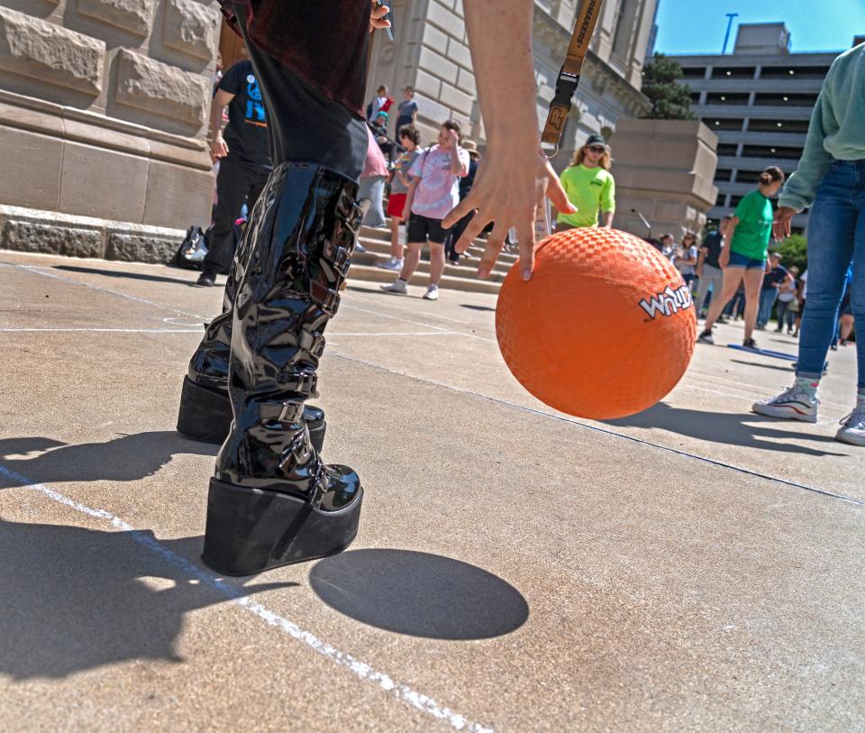 Abby Allen throws back a ball as she joins others as they play games on the south lawn Tuesday, May 24, 2022 at the Indiana Statehouse in Indianapolis, Ind.  Protesters spent the day at the Statehouse asking lawmakers to maintain Gov. Eric Holcomb's veto of HB 1041, the transgender sports ban. But Lawmakers later in the day overrode the veto. Protesters played games and rallied, listening to speakers, before the vote.