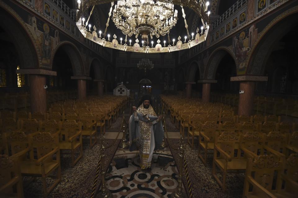 A Greek Orthodox priest takes part in the Good Saturday ceremony, held without worshippers inside an empty church in the northern city of Thessaloniki, Greece, during a lockdown order by the government to prevent the spread of the coronavirus, on Sunday, April 19, 2020. Greeks celebrated the Resurrection of Christ very differently Saturday night: confined at home, instead of massively congregating in churches. And they had to do without the "Holly Light" from Jerusalem, which arrived in Athens but was not distributed, as authorities remained ready to crack down on anyone who violated the strict curfew imposed almost a month ago. (AP Photo/Giannis Papanikos)