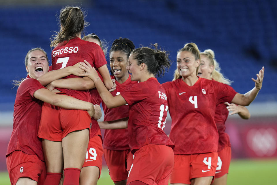 Teammates embrace Canada's Julia Grosso after she scored the winning goal against Sweden in the women's soccer match for the gold medal at the 2020 Summer Olympics, Friday, Aug. 6, 2021, in Yokohama, Japan. (AP Photo/Fernando Vergara)