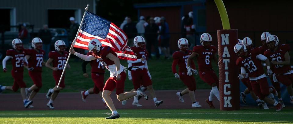 Natick senior captain Jack McCarthy leads the Redhawks onto the field before the game against Milford at Memorial Field in Natick, Sept. 23, 2022. 