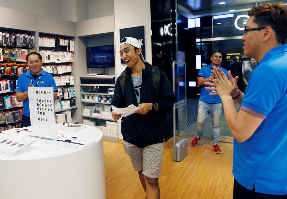 Kent Lee, 20, is congratulated as the first customer in the queue to purchase an iPhone 7 at an Apple reseller shop in Singapore September 16, 2016. REUTERS/Edgar Su