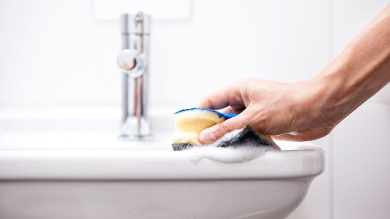  Clenaing a bathroom sink with a sponge 