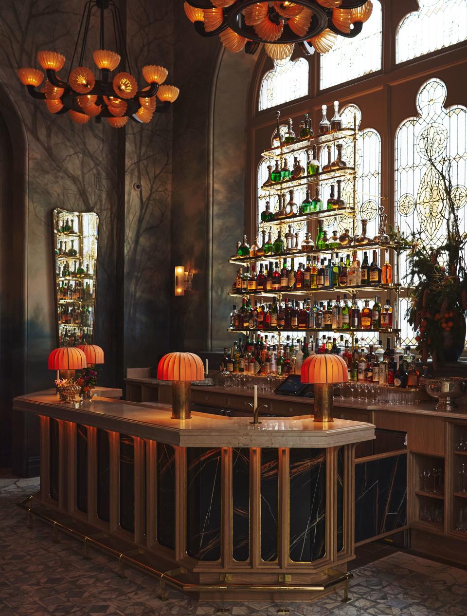 A Black St. Laurent marble bar and stained glass window alongside custom lighting adds intrigue to the cocktail area.