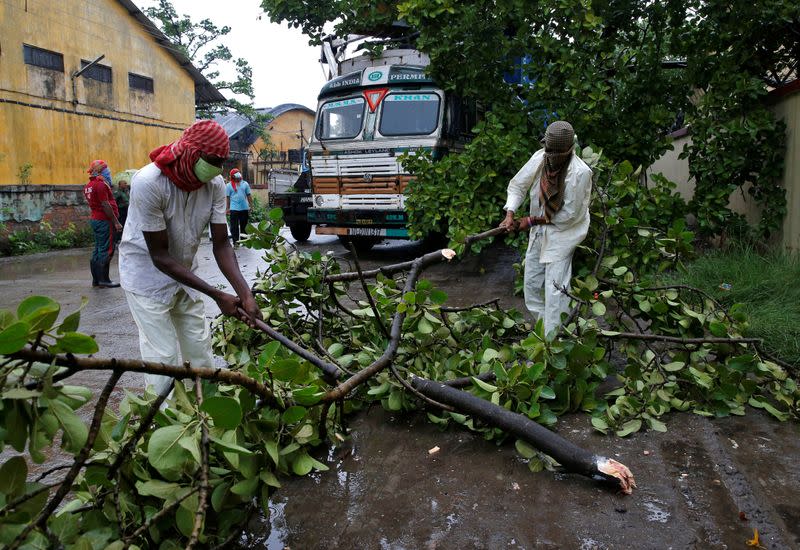 Rescue workers cut tree branches that fell on a truck trailer after heavy winds caused by Cyclone Amphan, in Kolkata