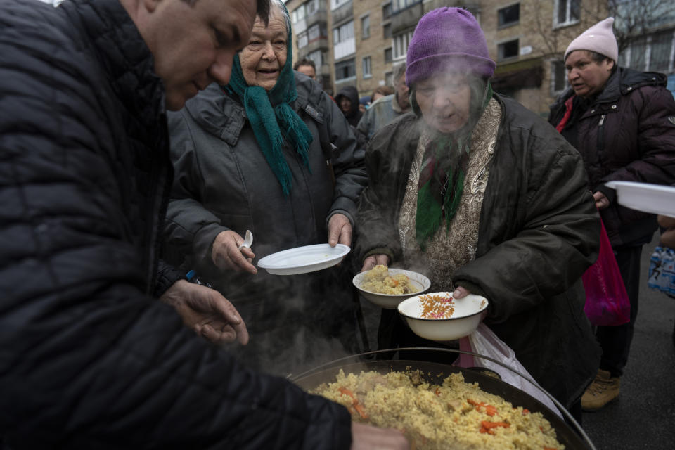 Neighbours receive free food from a soup kitchen in Bucha, in the outskirts of Kyiv, Ukraine, Saturday, April 9, 2022. (AP Photo/Rodrigo Abd)