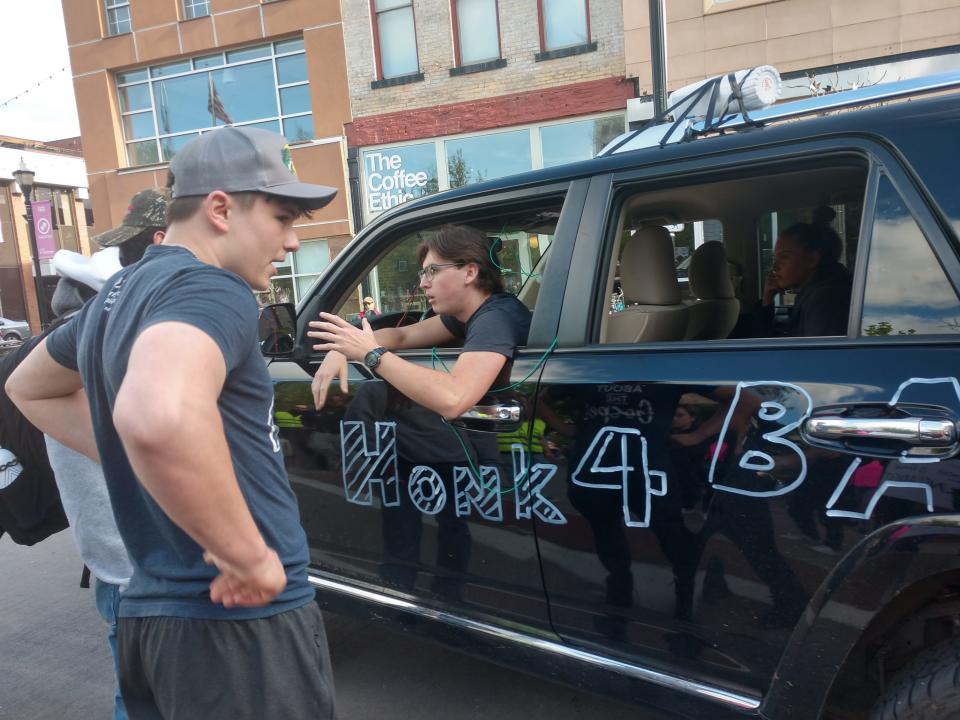 Pro-life counter protestors at a pro-choice rally observe their black SUV after the loudspeaker was disabled by rallygoers.