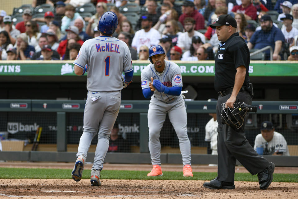 New York Mets' Jeff McNeil (1) crosses home plate while cheered on by Francisco Lindor, center, as they scored on a DJ Stewart two-run double against the Minnesota Twins as home plate umpire Janson Visconti , right, looks on during the ninth inning of a baseball game Sunday, Sept. 10, 2023, in Minneapolis. (AP Photo/Craig Lassig)