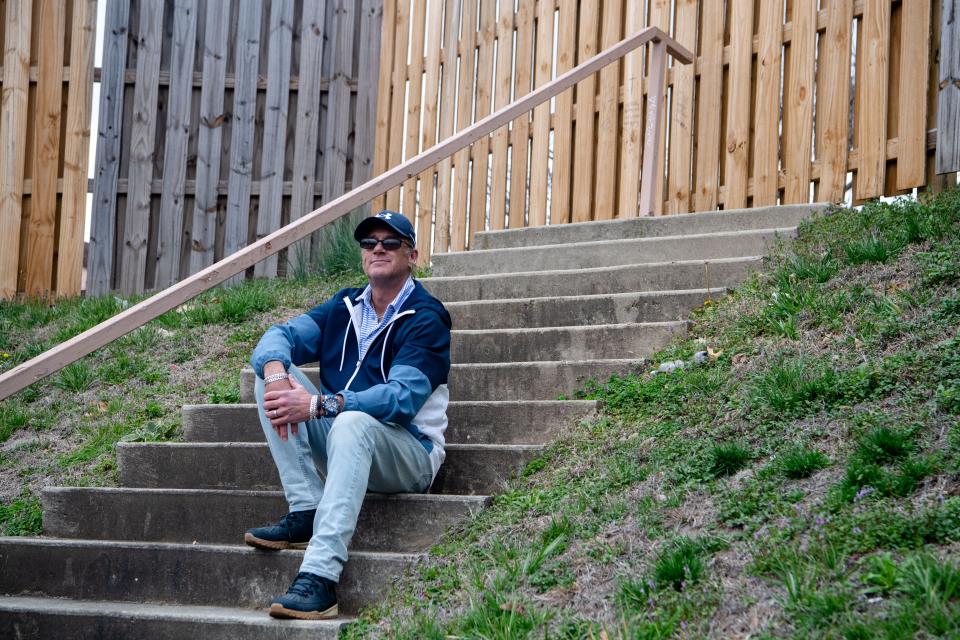 Eric Hall sits on a staircase that leads to a fence bordering the Ramada Inn in East Asheville, March 8, 2024.