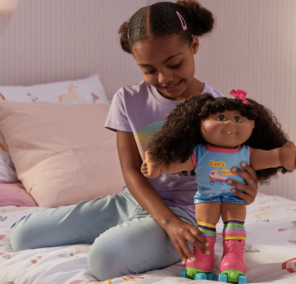 little girl playing with Cabbage Patch Kids Roller Skate Party on bed (Photo via Amazon)