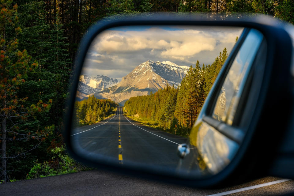 Driving a car through a mountain road that leads through the Canadian Rockies and watching the beautiful scenery in the rearview mirror in the icefields parkway, Jasper National Park, Alberta, Canada