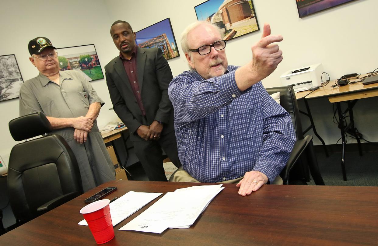 James Ragan tosses the coin into the air as Ronnie Laws, right, and Corey Creech watch to see who wins the position of Ranlo Town Commissioner Friday afternoon at the Gaston County Board of Elections on West Franklin Boulevard.