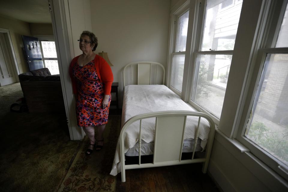 FILE - In this May 15, 2013 file photo, Patricia Hall stands for a photograph in the 5-by-14' room that Lee Harvey Oswald rented in 1963 at her family's rooming house in Dallas. Oswald stayed at the red brick house with white trim during the week while working his new job at the Texas School Book Depository, and on the weekends he returned to the suburb of Irving where his wife lived. Hall said she's been considering selling the house for years, but decided the time was right as this year marks the 50th anniversary of Kennedy's assassination in downtown Dallas. (AP Photo/Tony Gutierrez)