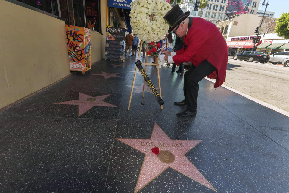 Gregg Donovan signs a card as flowers are placed on popular game show host Bob Barker's Walk of Fame star in Los Angeles, Saturday, Aug. 26, 2023. A publicist says Barker, a household name for a half-century as host of "Truth or Consequences" and "The Price Is Right," has died at his home in Los Angeles. Barker was 99. (AP Photo/Damian Dovarganes)