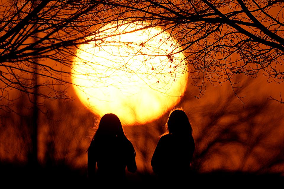 People watch the sunset at a park on an unseasonably warm day on Feb. 25, 2024, in Kansas City, Mo.