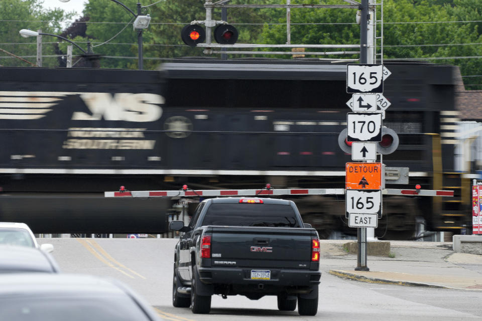FILE - Traffic backs up as a Norfolk Southern freight train rolls through a crossing in downtown East Palestine, Ohio, on June 22, 2023. The latest BNSF rail layoffs in late Feb. 2024, combined with an investment fund's ongoing campaign for control of Norfolk Southern, are renewing concerns among union and regulators about all the cuts hurting safety and service. (AP Photo/Gene J. Puskar, File)