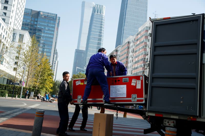 Men unload cargo from the truck of a logistics firm in Central Business District in Beijing