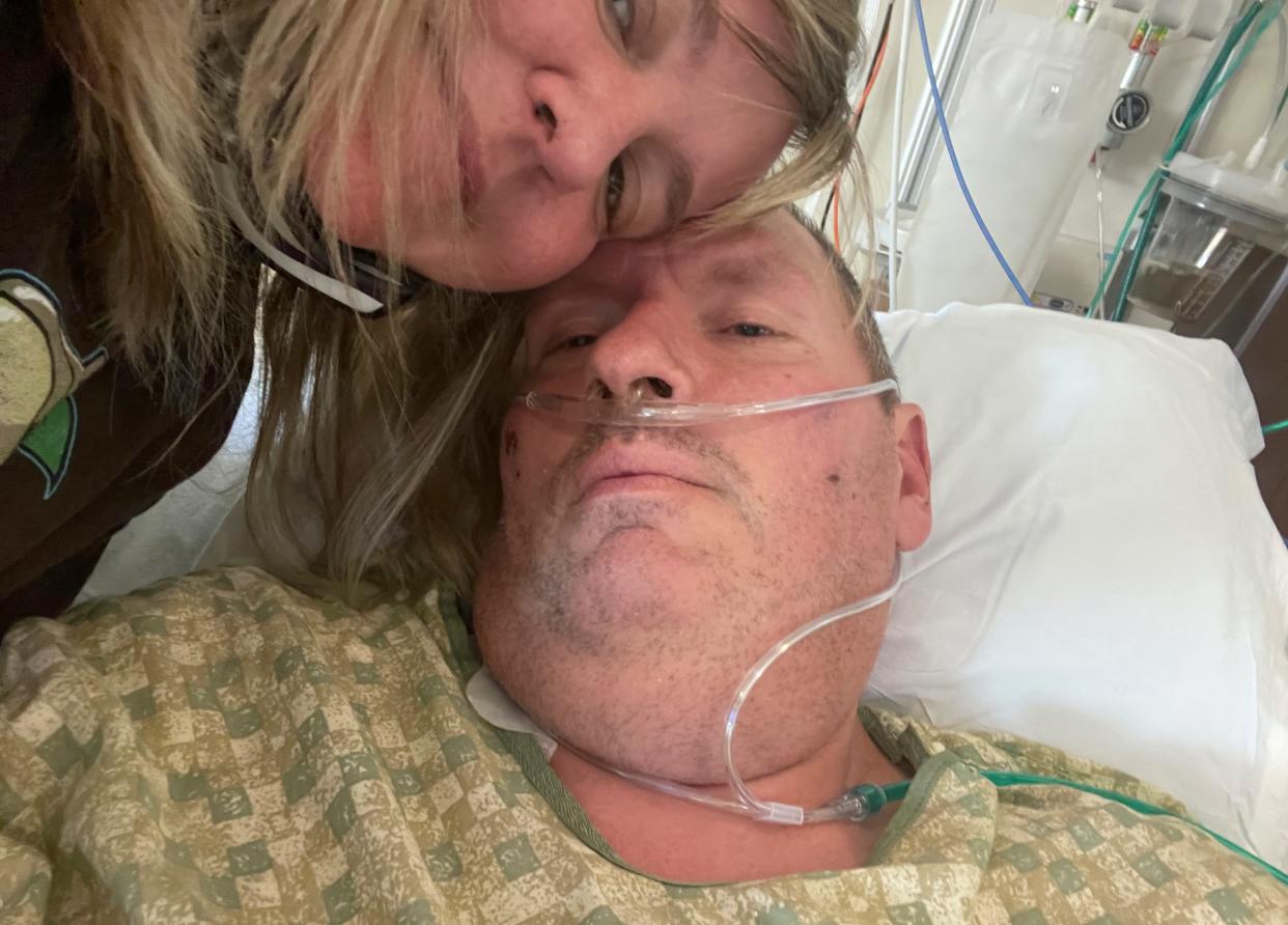 In this photo provided by Christina Fisher, Lincoln County Sheriff's Deputy Ben Fisher and his wife, Christine Fisher, are pictured in mid-Oct. 2021, at the Boise VA Medical Center where he was being treated for COVID-19, in Boise, Idaho. Fisher, who was unvaccinated and lax about wearing a mask outside of work, has changed his mind about the COVID-19 vaccine. He was diagnosed with COVID-19 in late September, spent 40 days bedridden, 17 days intubated and lost 80 pounds. He was transferred to another hospital for rehabilitation on Oct. 22, but not before receiving his first dose of the COVID-19 vaccine. (Christina Fisher via AP)