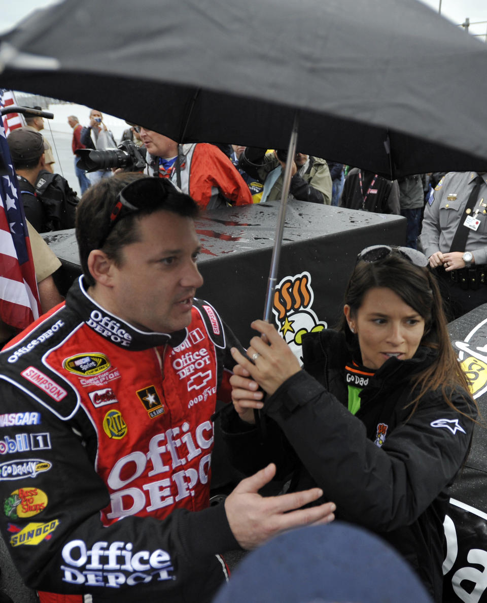 Danica Patrick, right, stands under an umbrella with Tony Stewart, left, during a rain delay in the start of the NASCAR Daytona 500 Sprint Cup series auto race in Daytona Beach, Fla., Sunday, Feb. 26, 2012. (AP Photo/Rainier Ehrhardt)