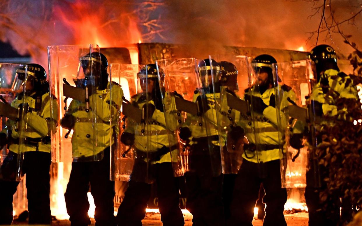 Police officers with flames behind them. - Liverpool Echo