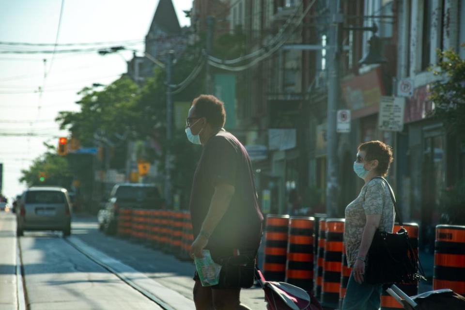 People cross the street in Toronto on Monday.