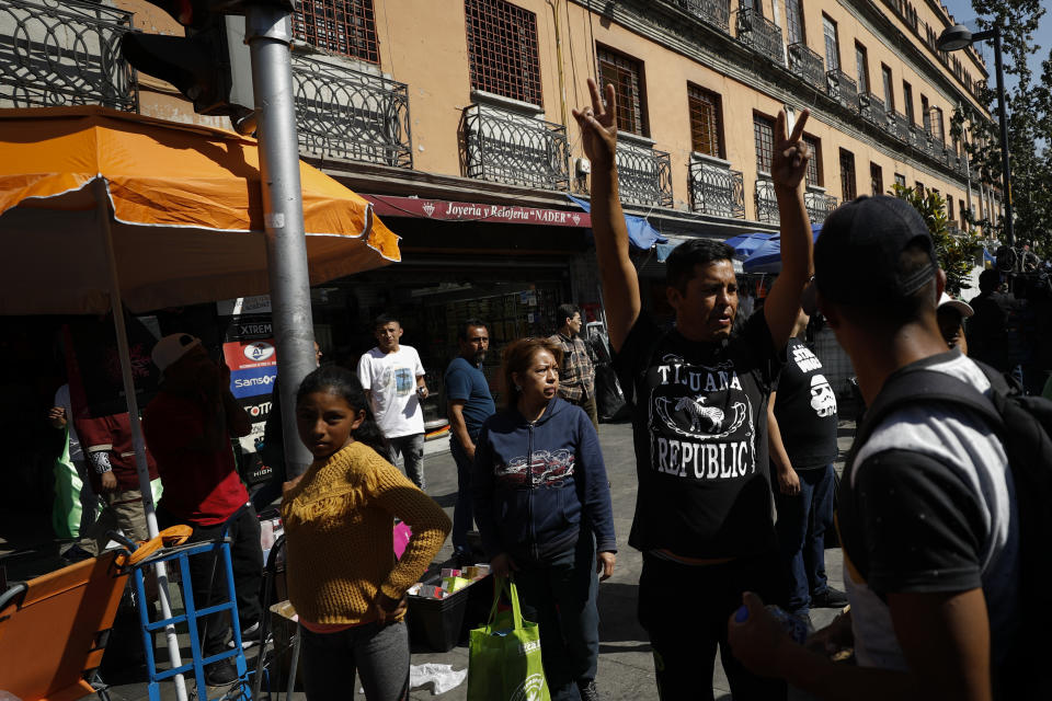 A bystander gestures toward the convoy carrying U.S. Attorney General William Barr as it passes through a crowded commercial street outside the National Palace, where Barr was to meet privately with President Andres Manuel Lopez Obrador and Foreign Minister Marcelo Ebrard, in Mexico City, Thursday, Dec. 5, 2019. Barr's closed-door meetings in Mexico come about one week after President Donald Trump suggested that the United States would seek to classify Mexican drug cartels as terrorist organizations. (AP Photo/Rebecca Blackwell)