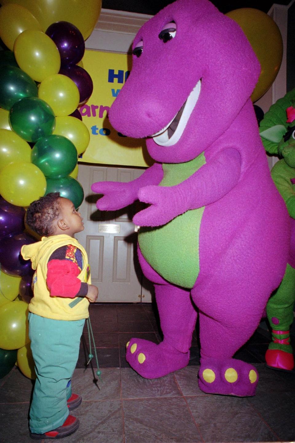 Television dinosaur Barney reaches out to a youngster at a performance for young patients at the New York Institute for Special Education in Feb., 1993.  Public Broadcasting Service stations are upsetting some parents by using toys based on Barney and other characters during breaks in children's programs as spring pledge drive incentives.