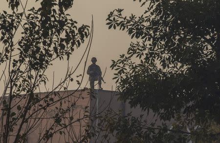 An army soldier stands guard on the roof of one of the buildings of the Army Public School which was attacked by Taliban gunmen, in Peshawar December 17, 2014. REUTERS/Zohra Bensemra