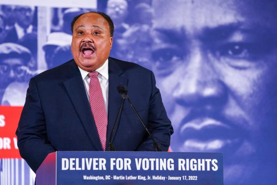 A man stands behind a podium with a large picture of Martin Luther King Jr in the background.