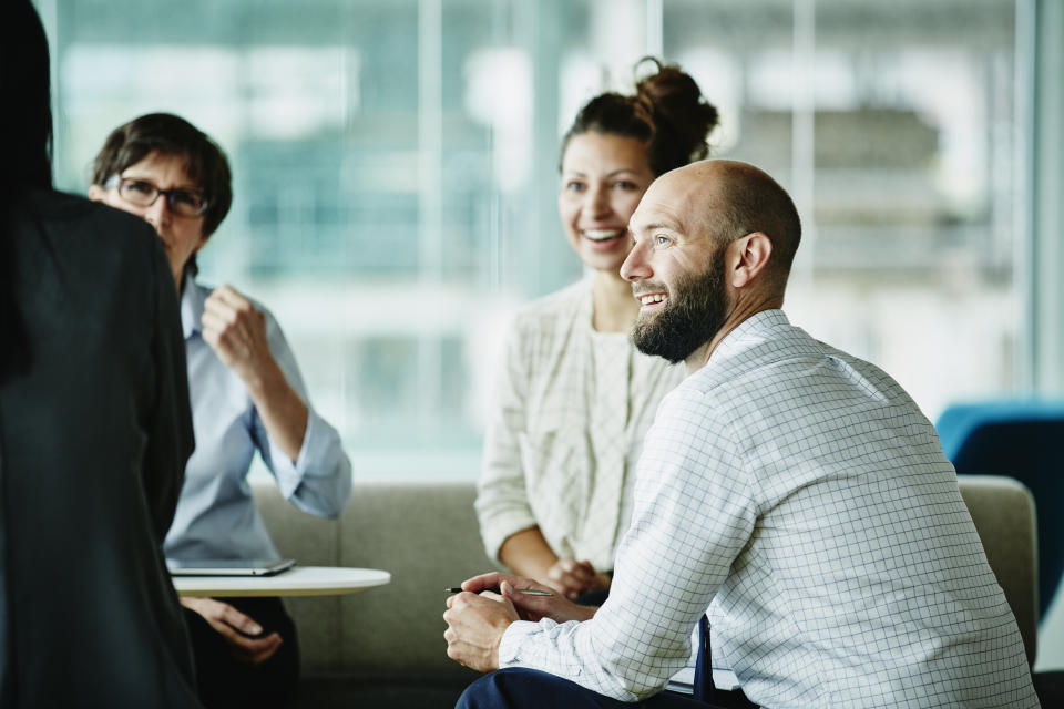 Smiling businessman in discussion with colleagues during informal project meeting in office