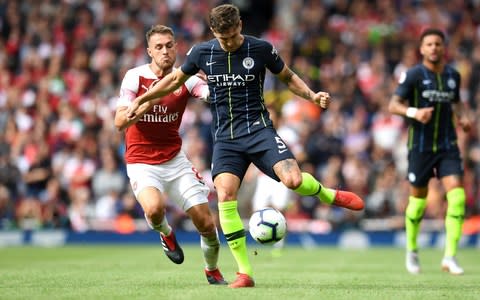 John Stones of Manchester City passes the ball under pressure from Aaron Ramsey of Arsenal during the Premier League match between Arsenal FC and Manchester City at Emirates Stadium on August 12, 2018 in London, United Kingdom - Credit: Getty Images