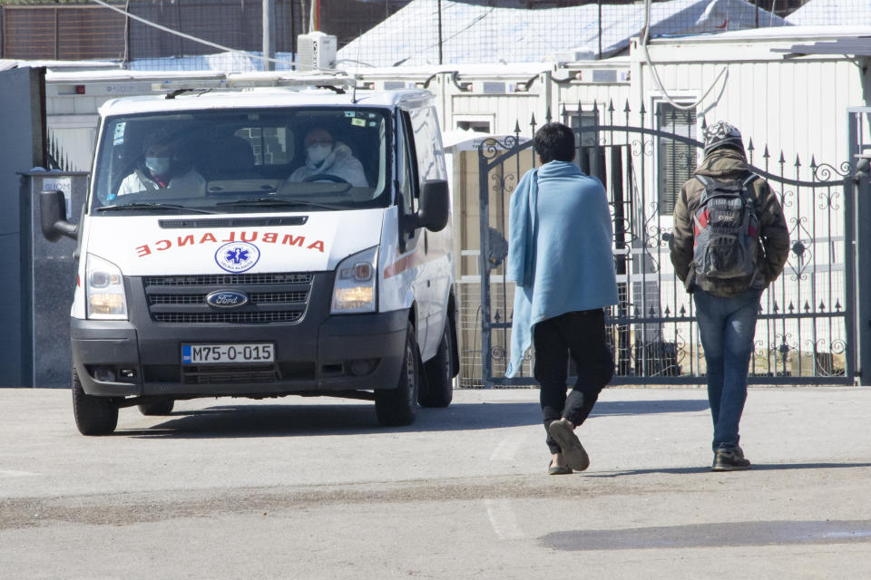 An ambulance exits the Miral migrant camp, in Velika Kladusa, Bosnia, Wednesday, April 7, 2021. Bosnia is seeing a rise in coronavirus infections among migrants and refugees living in its camps, as it struggles to cope with one of the Balkans' highest COVID-19 death and infection rates among the general population.(AP Photo/Davor Midzic)