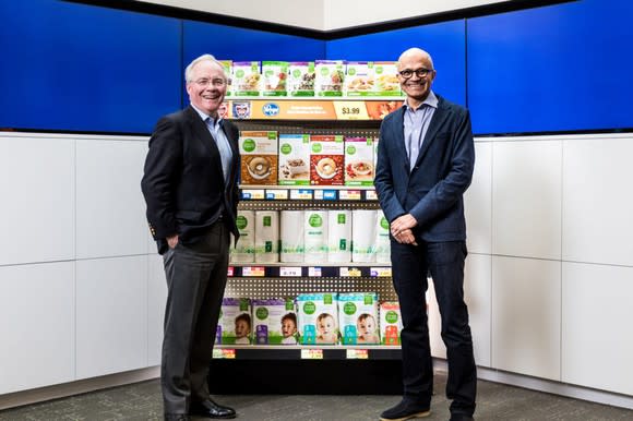 Kroger CEO Rodney McMullen and Microsoft CEO Satya Nadella standing on either side of sample store shelving.