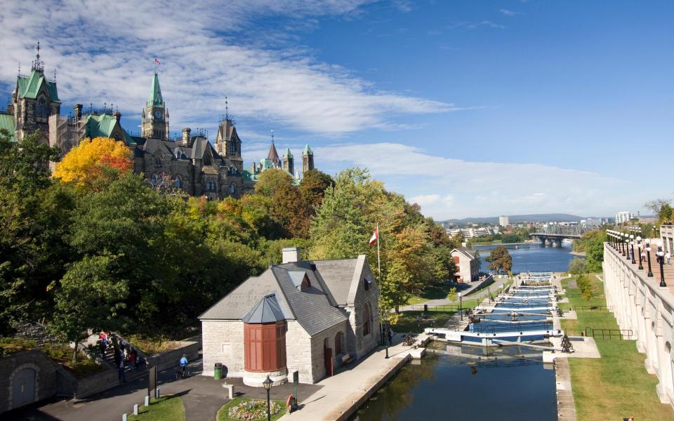 canal, trees and grand parliament building with spires - iStock